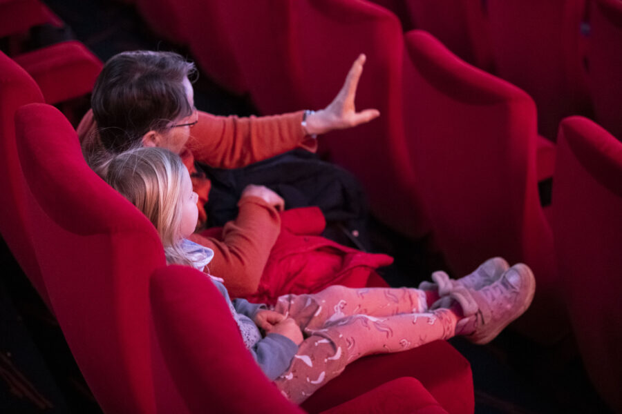 ein Erwachsener und ein Kind, die in einem Kinosaal sitzen
