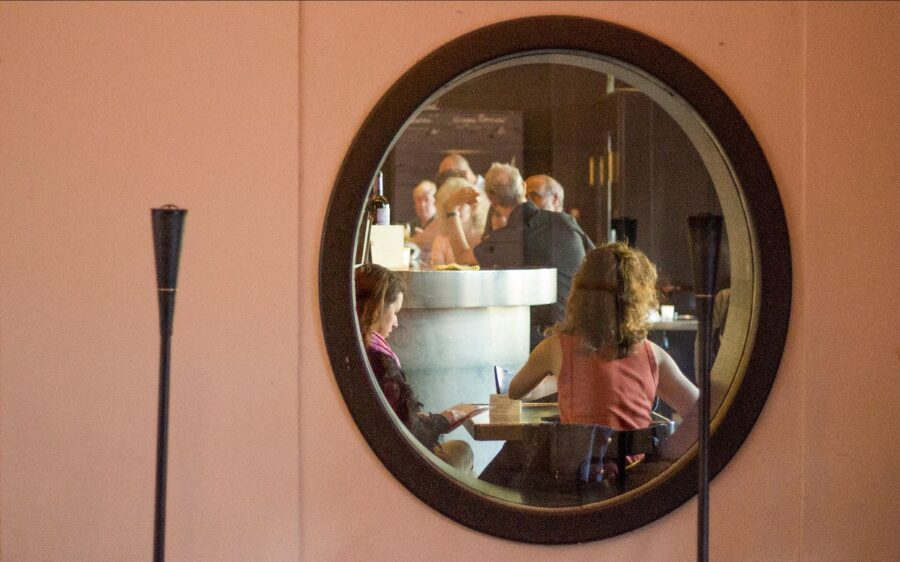 In einem Spiegel spiegeln sich Personen in einem Café