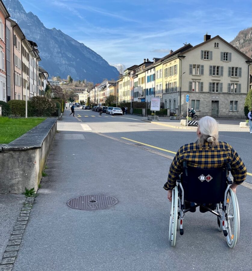 Ein Mann im Rollstuhl fährt auf dem Trottoir durch Glarus.