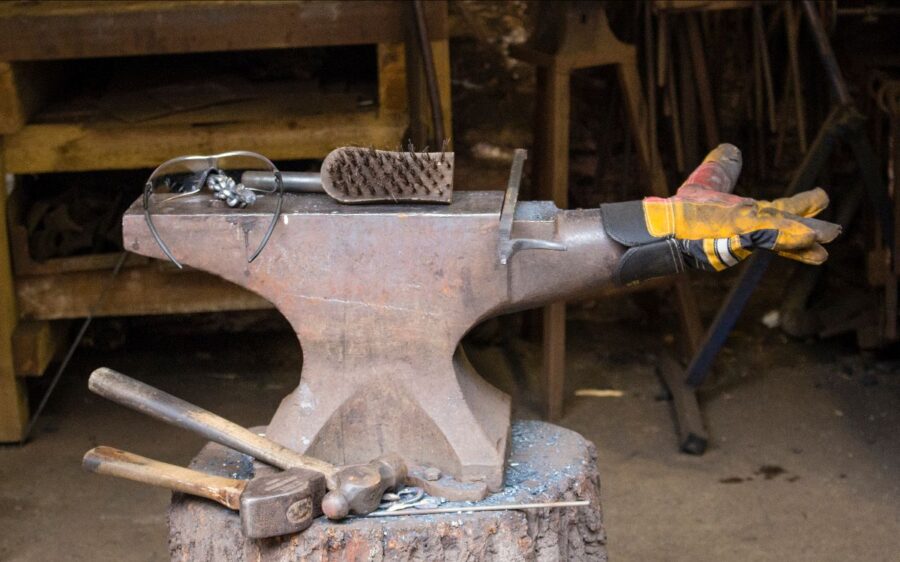 Auf dem Bild sind mehrere Werkzeuge und Arbeitsmaterial zu sehen. So zum Beispiel zwei Hammer, eine Bürste und ein gelber Handschuh.