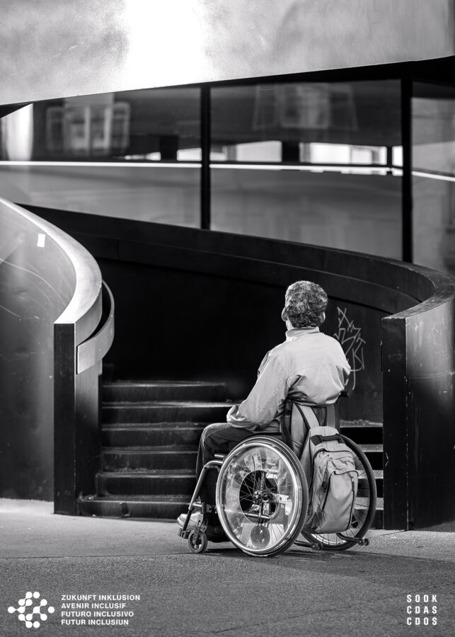 Mann in Rollstuhl vor Treppe