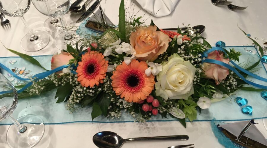 Buntes Blumengesteck auf weisser Tischdecke