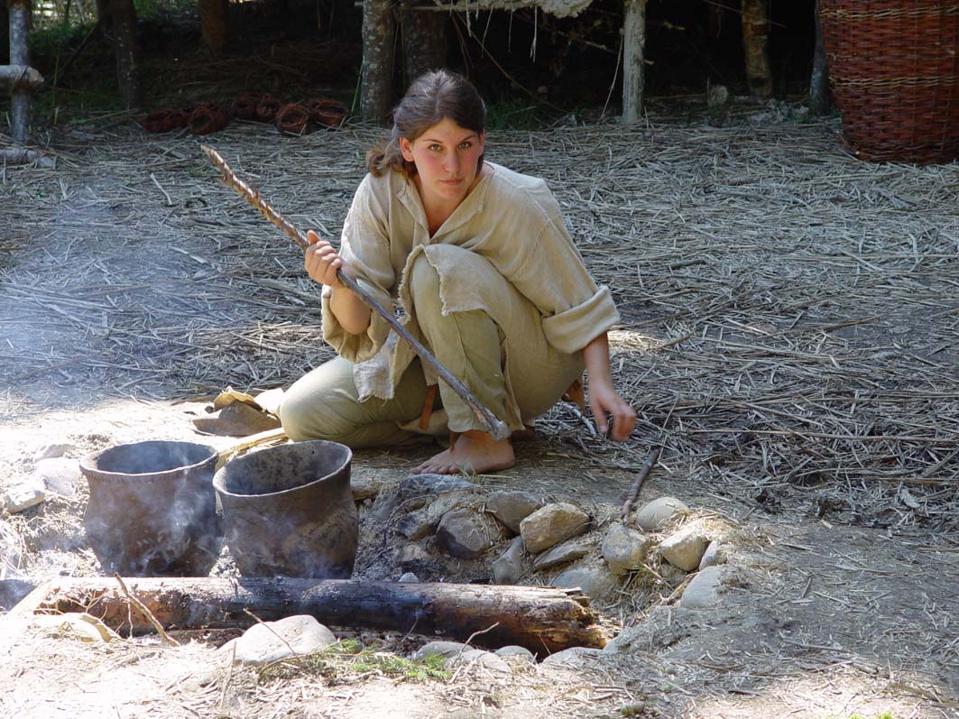 Frau mit einem Speer an einem Lagerfeuer