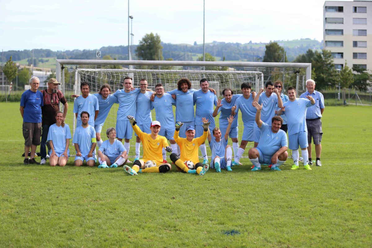 Auf dem Foto ist das Special Team von Zug 94 zu sehen. Sie stehen als Mannschaft vor einem Fussballtor.