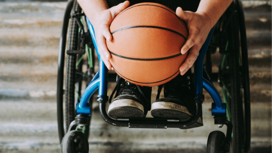 Rollstuhlfahrer mit Basketball in der Hand, platziert vor Treppe.