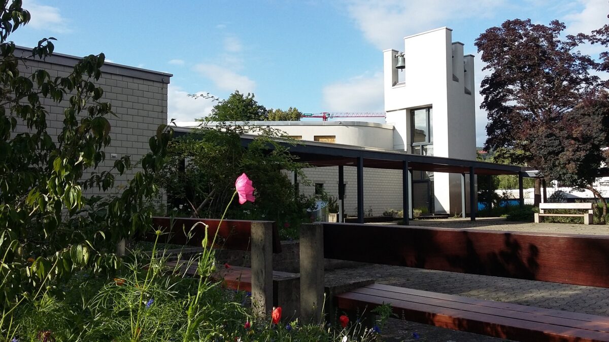 Foto der EPI Kirche, im Vordergrund blühen bunte Mohnblumen.