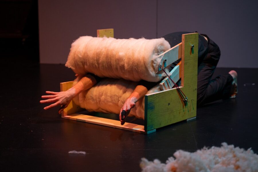Der Schauspieler Corsin Gaudenz quetscht sich durch eine selbstgebaute Maschine mit zwei Rollen aus Watte. Er veranschaulicht damit Gefühle und Bedürfnisse von Menschen mit Autismus.