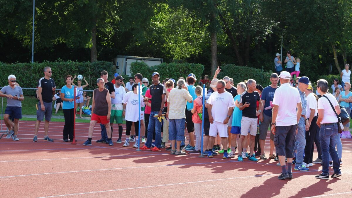 Auf dem Bild sind zahlreiche Menschen versammelt. Sie befinden sich draussen auf einer Sportanlage.