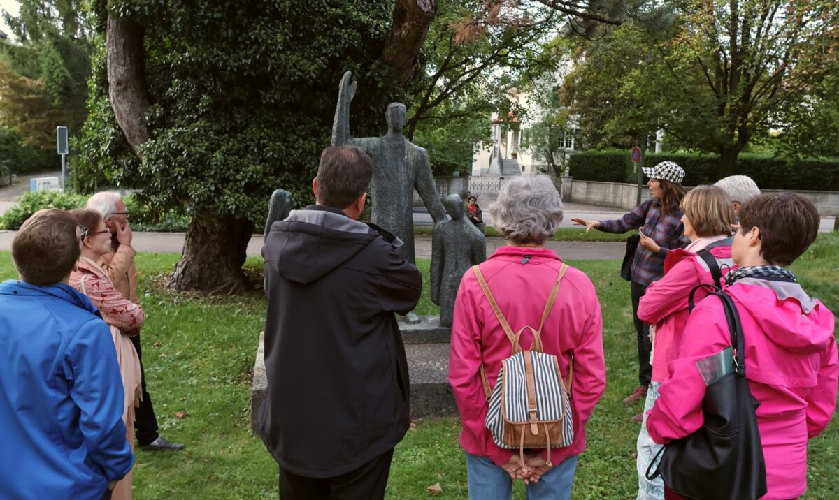 Die Künstlerin Karen Geyer steht neben einer Skulptur. Sie unterhält sich mit Teilnehmenden einer Kunstführung durch Uster.